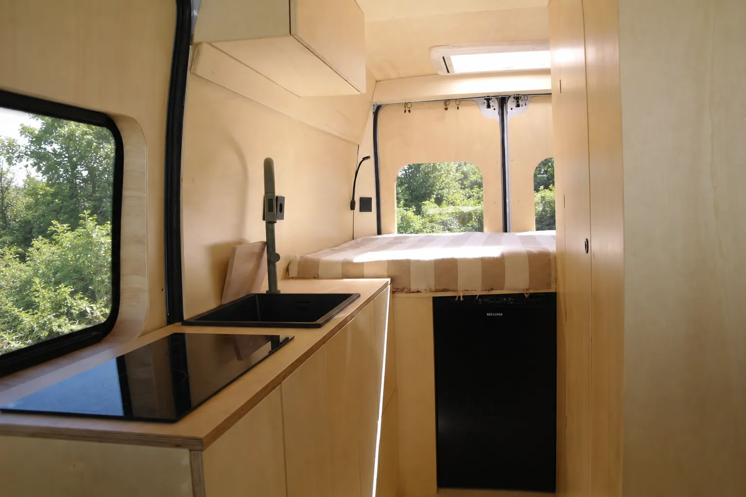 Cucina in legno e zona letto all’interno del van